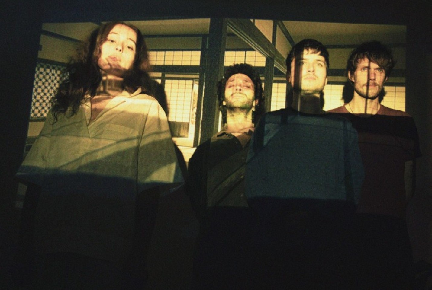 Azamiah band members looking into the camera with a room being projected onto their faces.